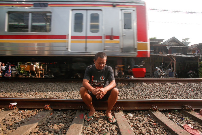 Warga berjemur di dekat jalur kereta api di kawasan Pejompongan, Jakarta Pusat, Selasa (6/7/2021).