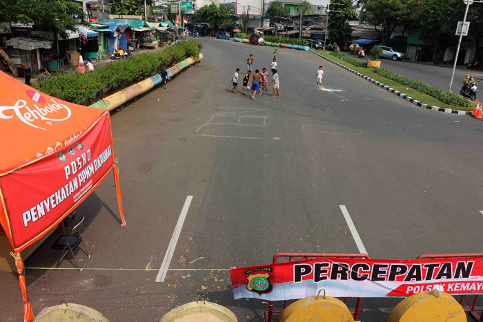 Anak-anak bermain sepak bola di jalan raya yang ditutup dikawasan Kemayoran, Jakarta Pusat, Rabu (7/7/2021).