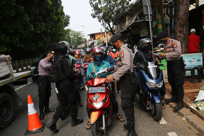 Petugas kepolisian memeriksa dokumen dan persyaratan pengendara di pos penyekatan PPKM Darurat di Jalan Raya Lenteng Agung, Jakarta, Rabu (7/7/2021).