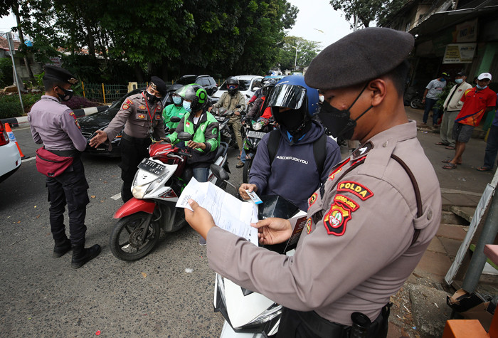 Petugas kepolisian memeriksa dokumen dan persyaratan pengendara di pos penyekatan PPKM Darurat di Jalan Raya Lenteng Agung, Jakarta, Rabu (7/7/2021).