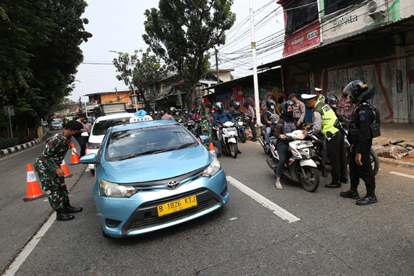 Petugas kepolisian memeriksa dokumen dan persyaratan pengendara di pos penyekatan PPKM Darurat di Jalan Raya Lenteng Agung, Jakarta, Rabu (7/7/2021).