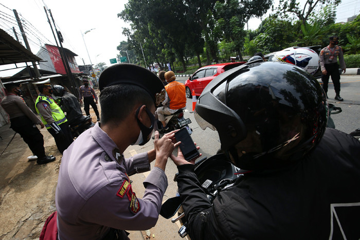 Petugas kepolisian memeriksa dokumen dan persyaratan pengendara di pos penyekatan PPKM Darurat di Jalan Raya Lenteng Agung, Jakarta, Rabu (7/7/2021).