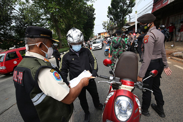 Petugas kepolisian memeriksa dokumen dan persyaratan pengendara di pos penyekatan PPKM Darurat di Jalan Raya Lenteng Agung, Jakarta, Rabu (7/7/2021).
