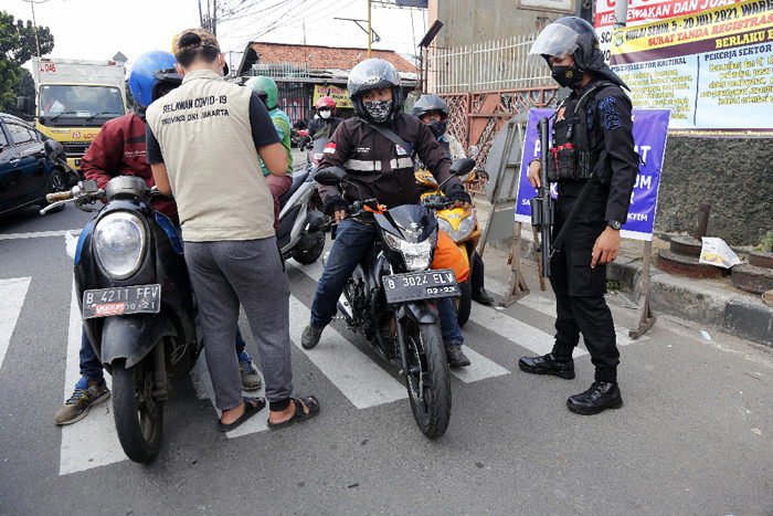 Petugas gabungan memutar arah kendaraan saat penyekatan di ruas Jalan Raya Bogor, Jakarta, Rabu (7/7/2021).