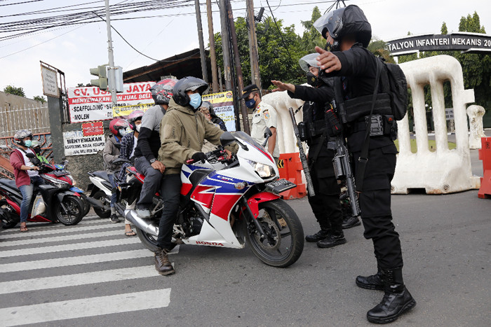 Petugas gabungan memutar arah kendaraan saat penyekatan di ruas Jalan Raya Bogor, Jakarta, Rabu (7/7/2021).
