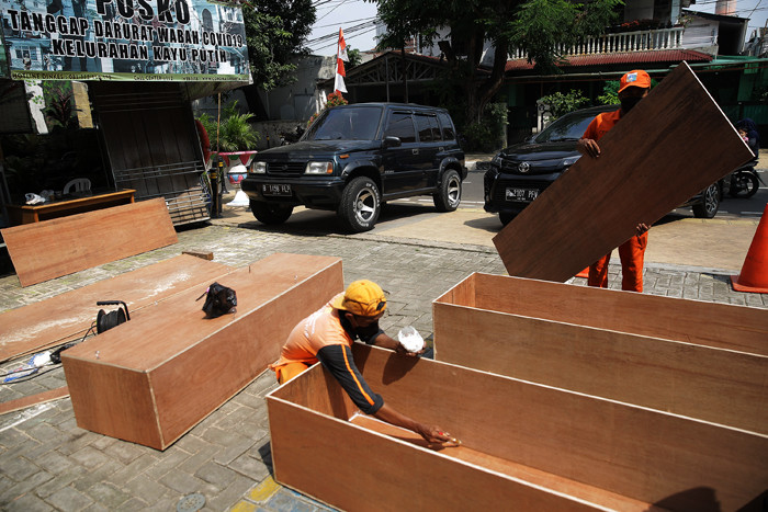 Petugas PPSU menyelesaikan pengerjaan peti jenazah untuk pasien Covid-19 di Kantor Kelurahan Kayu Putih, Jakarta, Selasa (6/7/2021).
