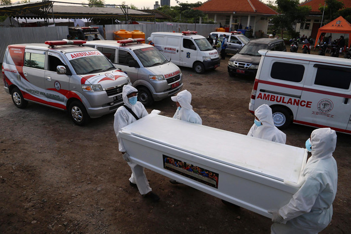 Petugas mengangkat peti jenazah untuk dilakukan perawatan sebelum di makamkan di tempat pemulasaraan darurat Keputih Surabaya, Jawa Timur, Kamis (8/7/2021).