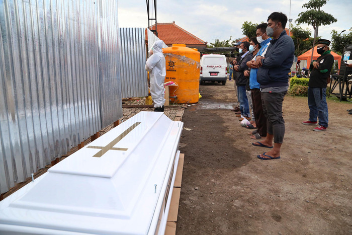 IDXChannel - Kerabat melakukan shalat jenazah diluar pagar tempat pemulasaraan darurat Keputih Surabaya, Jawa Timur, Kamis (8/7/2021).  Petugas pemulasaran jena