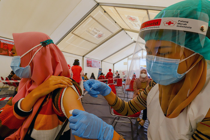 Petugas Palang Merah Indonesia menyuntikan vaksin Covid-19 kepada warga saat vaksinasi massal di Gudang Darurat Nasional, Jakarta Selatan, Jumat (9/7/2021).