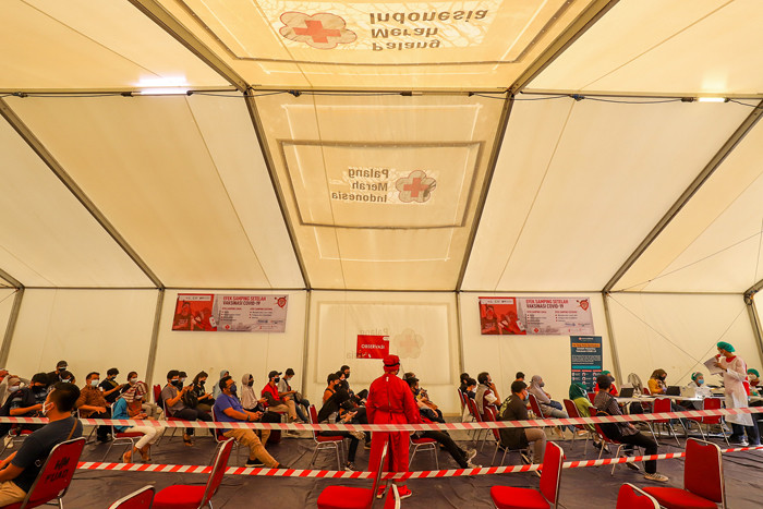 Petugas Palang Merah Indonesia menyuntikan vaksin Covid-19 kepada warga saat vaksinasi massal di Gudang Darurat Nasional, Jakarta Selatan, Jumat (9/7/2021).