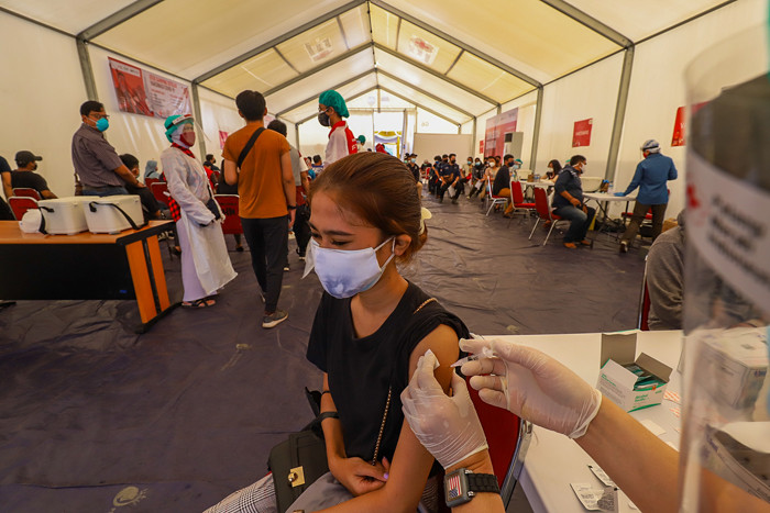 Petugas Palang Merah Indonesia menyuntikan vaksin Covid-19 kepada warga saat vaksinasi massal di Gudang Darurat Nasional, Jakarta Selatan, Jumat (9/7/2021).
