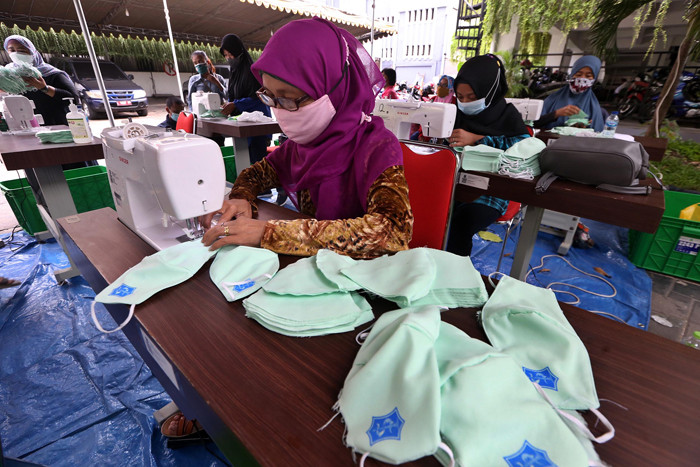 Sejumlah penjahit menyelesaikan pembuatan masker di Balai Kota Surabaya, Jawa Timur, Jumat (9/7/2021).