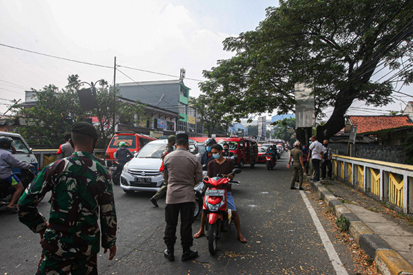 Petugas memeriksa KTP warga yang ingin melewati penyekatan di Jalan Molek, Pondok Gede, Kota Bekasi, Jawa Barat, Minggu (11/7/2021).