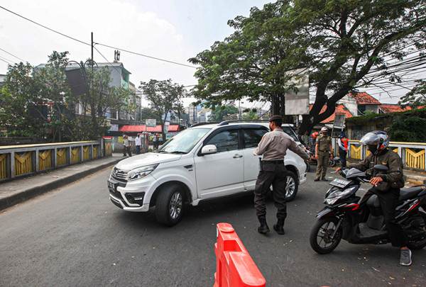 Petugas memeriksa KTP warga yang ingin melewati penyekatan di Jalan Molek, Pondok Gede, Kota Bekasi, Jawa Barat, Minggu (11/7/2021).