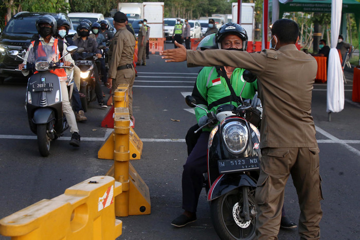Petugas mengarahkan pengendara untuk putar balik saat akan masuk kota Surabaya melalui akses masuk dari Surabaya Timur di Jawa Timur, Senin (12/7/2021).