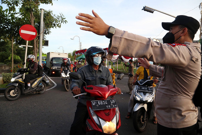 Petugas mengarahkan pengendara untuk putar balik saat akan masuk kota Surabaya melalui akses masuk dari Surabaya Timur di Jawa Timur, Senin (12/7/2021).