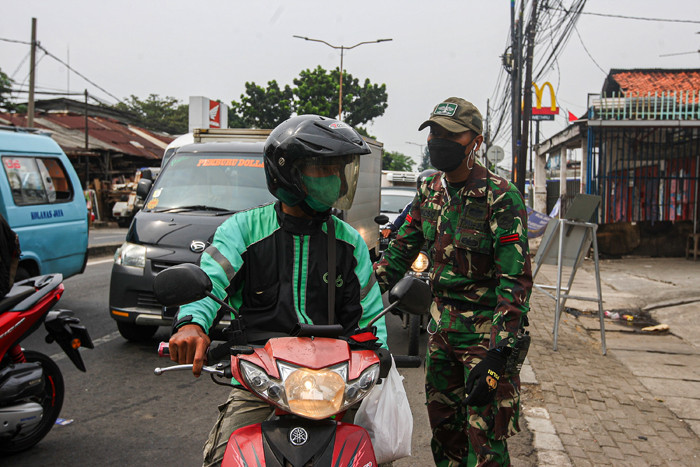 Warga saat menunjukan Surat Tanda Registrasi Pegawai (STRP) di penyekatan Jalan Raya Bogor, Jakarta Timur, Selasa (13/7/2021).