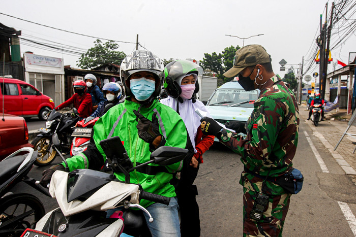 Warga saat menunjukan Surat Tanda Registrasi Pegawai (STRP) di penyekatan Jalan Raya Bogor, Jakarta Timur, Selasa (13/7/2021).