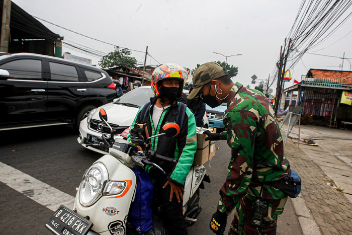 Warga saat menunjukan Surat Tanda Registrasi Pegawai (STRP) di penyekatan Jalan Raya Bogor, Jakarta Timur, Selasa (13/7/2021).