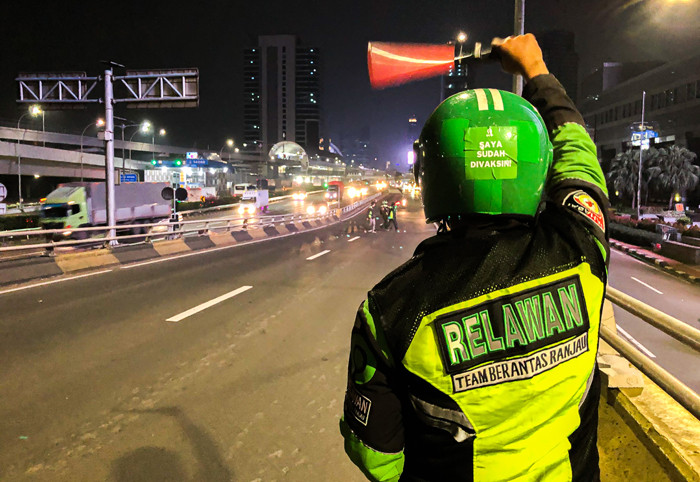 Driver Ojek Online yang tergabung dalam komunitas Tebar saat mencari ranjau paku yang bertebaran di Jalan Gatot Subroto, Jakarta, Selasa (13/7/2021).