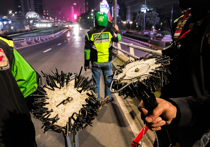 Driver Ojek Online yang tergabung dalam komunitas Tebar saat mencari ranjau paku yang bertebaran di Jalan Gatot Subroto, Jakarta, Selasa (13/7/2021).
