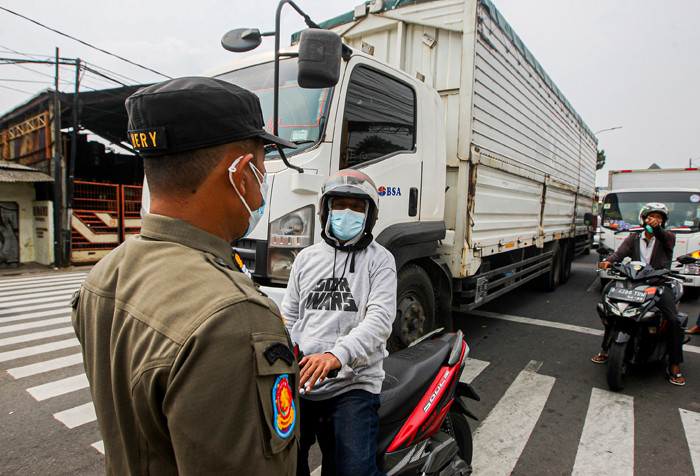 Aparat kepolisian memerksa kelengkapan surat warga saat melintas di pos penyekatan PPKM Darurat Jalan Raya Bogor, Jakarta Timur, Rabu (14/7/2021).