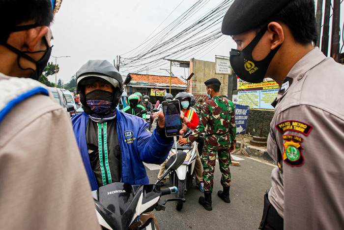Aparat kepolisian memerksa kelengkapan surat warga saat melintas di pos penyekatan PPKM Darurat Jalan Raya Bogor, Jakarta Timur, Rabu (14/7/2021).
