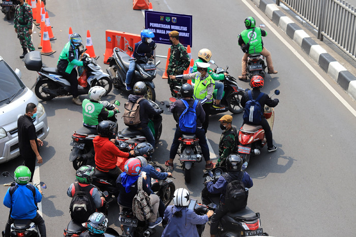 Petugas kepolisian dibantu TNI dan Satpol PP mengalihkan arus kendaraan akibat diberlakukannya titik penyekatan di kawasan Mampang Prapatan, Kamis (15/7/2021).