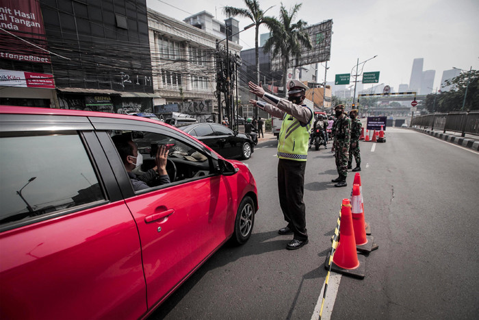 Petugas kepolisian dibantu TNI dan Satpol PP mengalihkan arus kendaraan akibat diberlakukannya titik penyekatan di kawasan Mampang Prapatan, Kamis (15/7/2021).
