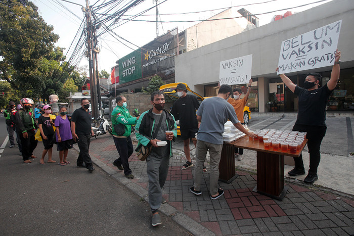 Barista membagikan makanan siap saji di depan Kopi Muja, Kebayoran Baru, Jakarta Selatan, Jumat (16/7/2021).