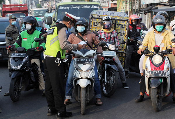 Petugas gabungan mengatur arus lalu lintas saat penyekatan masa PPKM Darurat di kawasan Sandartex Ciputat Tangerang Selatan, Jakarta, Jumat (16/7/2021).