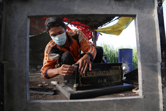 Perajin menyelesaikan pembuatan batu nisan disalah satu rumah produksi Keputih Surabaya, Jawa Timur, Jumat (16/7/2021).