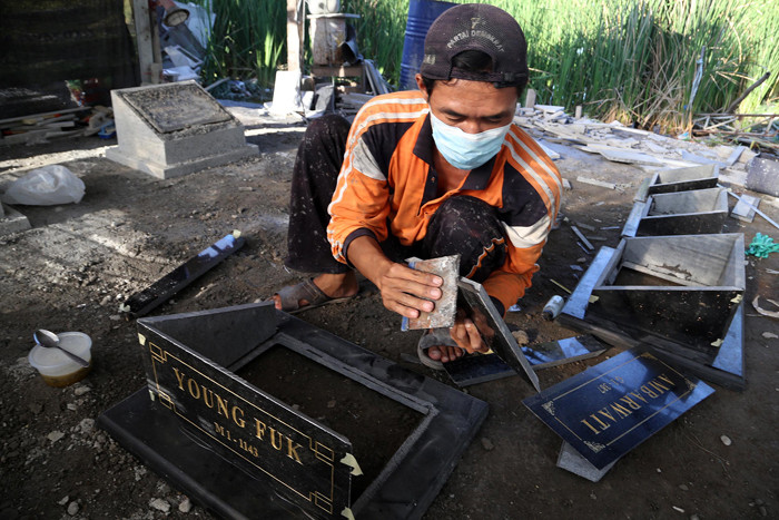 Perajin menyelesaikan pembuatan batu nisan disalah satu rumah produksi Keputih Surabaya, Jawa Timur, Jumat (16/7/2021).