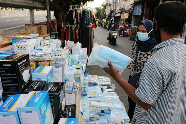 Pedagang masker melayani pembeli di kawasan Pasar Pagi Lama, Jakarta, Sabtu (17/7/2021).