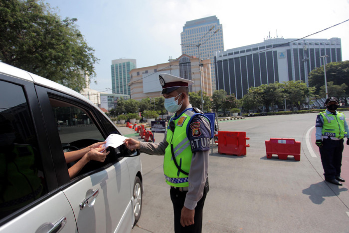 Petugas kepolisian memeriksa kendaraan di pos penyekatan PPKM Darurat di kawasan Jalan Jenderal Sudirman, Jakarta, Sabtu (17/7/2021).