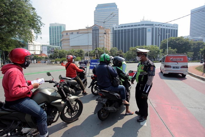 Petugas kepolisian memeriksa kendaraan di pos penyekatan PPKM Darurat di kawasan Jalan Jenderal Sudirman, Jakarta, Sabtu (17/7/2021).
