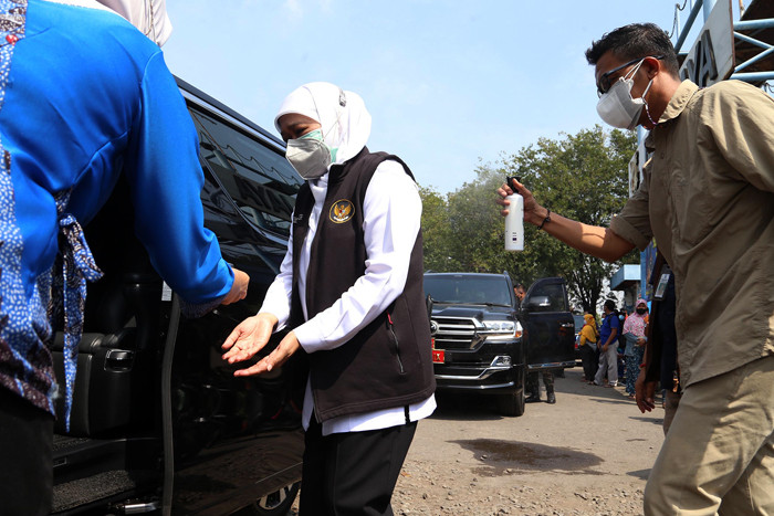 Ajudan menyemprotkan cairan disinfektan kepada Gubernur Jawa Timur Khofifah Indar Parawansa sebelum masuk ke mobil di Jawa Timur, Minggu (18/7/2021).