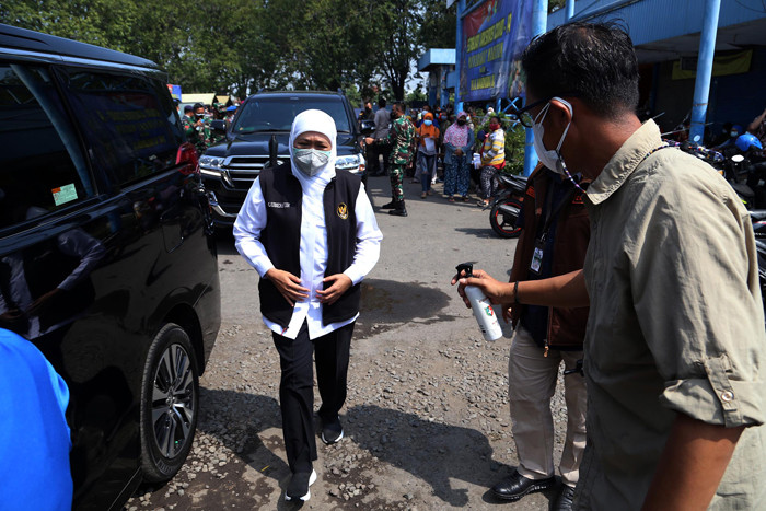 Ajudan menyemprotkan cairan disinfektan kepada Gubernur Jawa Timur Khofifah Indar Parawansa sebelum masuk ke mobil di Jawa Timur, Minggu (18/7/2021).