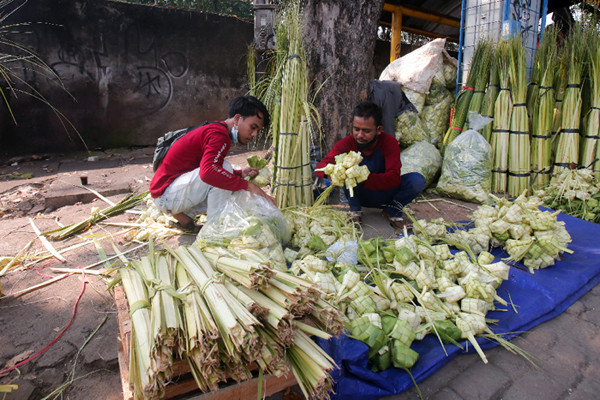 Penjual menyelesaikan pembuatan kulit ketupat di Pasar Palmerah, Jakarta Pusat, Minggu (18/7/2021).