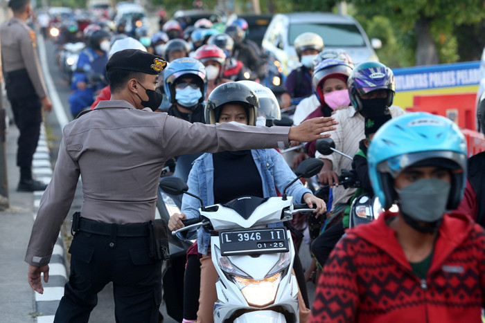 Petugas melakukan pengecekan dokumen pengendara yang melintas di pos penyekatan Jembatan Suramadu, sisi Surabaya, Jawa Timur, Senin (19/7/2021).