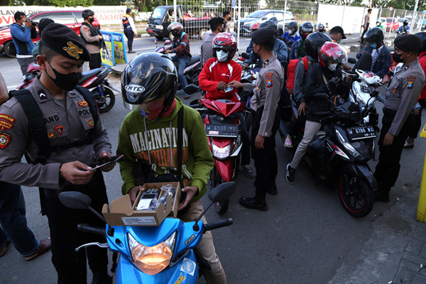 Petugas melakukan pengecekan dokumen pengendara yang melintas di pos penyekatan Jembatan Suramadu, sisi Surabaya, Jawa Timur, Senin (19/7/2021).