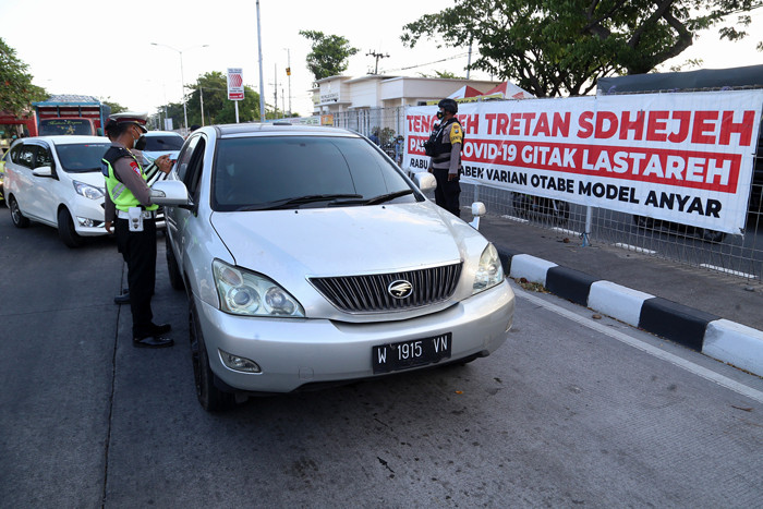 Petugas melakukan pengecekan dokumen pengendara yang melintas di pos penyekatan Jembatan Suramadu, sisi Surabaya, Jawa Timur, Senin (19/7/2021).