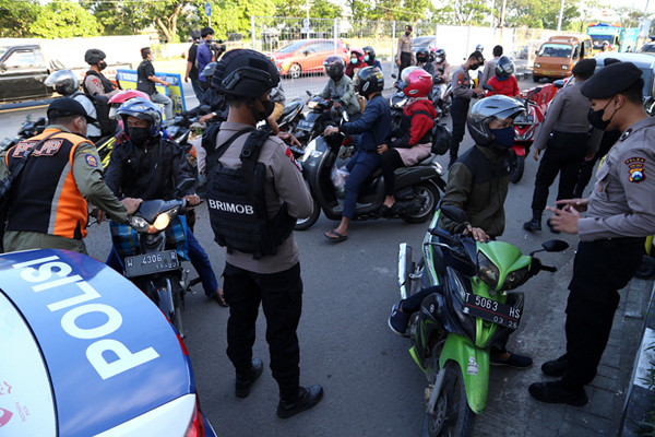 Petugas melakukan pengecekan dokumen pengendara yang melintas di pos penyekatan Jembatan Suramadu, sisi Surabaya, Jawa Timur, Senin (19/7/2021).