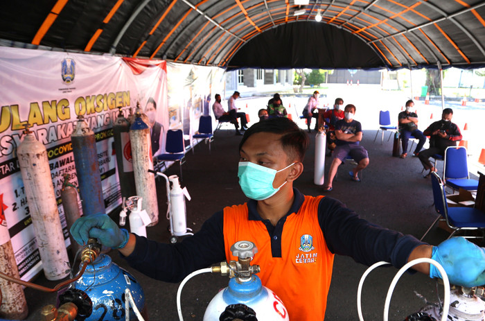 Petugas mengisi ulang tabung oksigen di halaman Dinas Perhubungan Jatim Jalan Ahmad Yani Surabaya, Jawa Timur, Senin (19/7/2021).