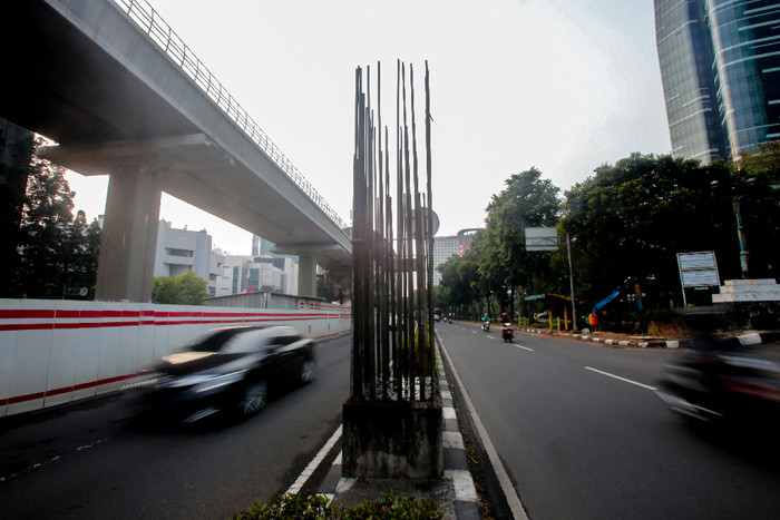 Pengendara melintas di dekat tiang-tiang bekas proyek monorel di Jalan Rasuna Said, Kuningan, Jakarta, Senin (19/7/2021).