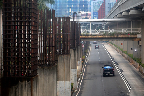 Pengendara melintas di dekat tiang-tiang bekas proyek monorel di Jalan Rasuna Said, Kuningan, Jakarta, Senin (19/7/2021).