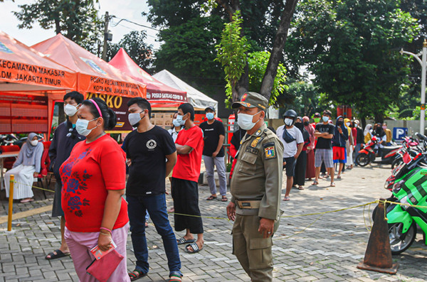 Petugas Satpol PP mengatur antrean warga yang ingin mencairkan Bantuan Langsung Tunai di Kecamatan Makasar, Jakarta Timur, Selasa (20/7/2021).