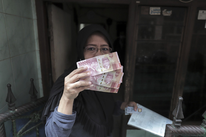 Juru Bayar Kantor Pos Indonesia memotret warga penerima Bantuan Sosial Tunai (BST) di wilayah Kelurahan Petojo Selatan, Jakarta, Rabu (21/7/2021).