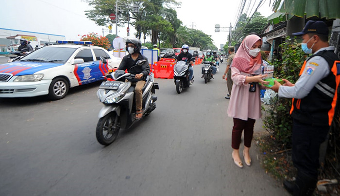 Pegawai PT Bank Tabungan Negara (Persero) Tbk membagikan makanan dan hand sanitizer kepada petugas di kawasan Samsat Daan Mogot, Jakarta, Kamis (22/7/2021).