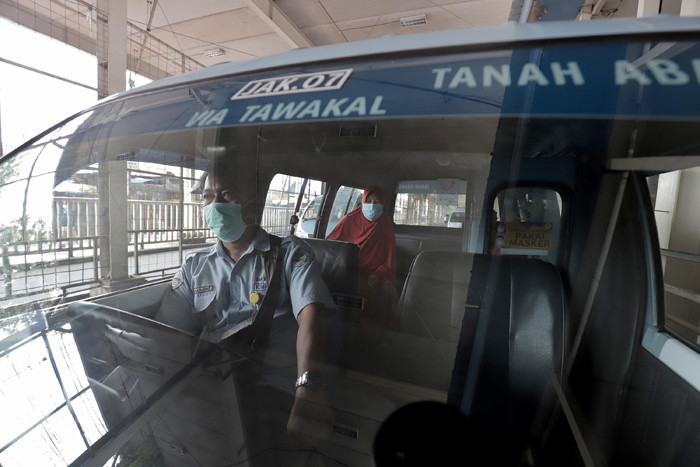 Supir angkutan Jak Lingko mengenakan masker saat menunggu penumpang di Tanah Abang, Jakarta, Kamis (22/7/2021).